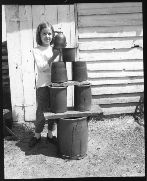 Mary Decker, a great, great granddaughter of Charles Sr. holding a utilitarian jug behind a pyramid of Decker jars c 1970. Seen in the Tennessee Conservationist. Burbage9.